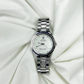 Silver watch with a white face on a white fabric background