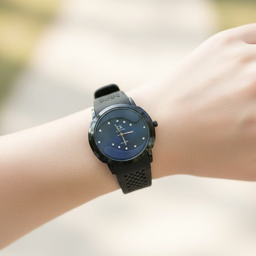 Wrist wearing a black watch with a blue face on a blurred background