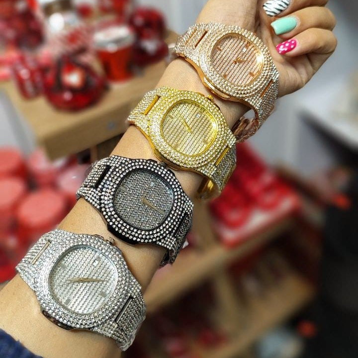 Wrist wearing multiple diamond-encrusted watches with a blurred background