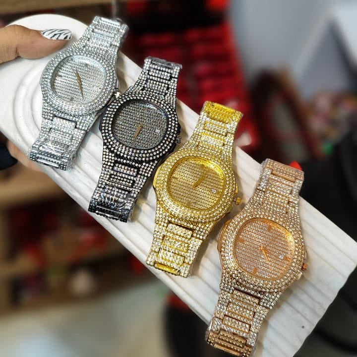 Four ornate watches with diamond-studded bands on a white surface.