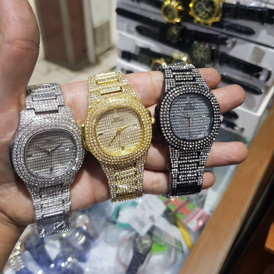 Three ornate watches in silver, gold, and black held in a hand with a blurred background.