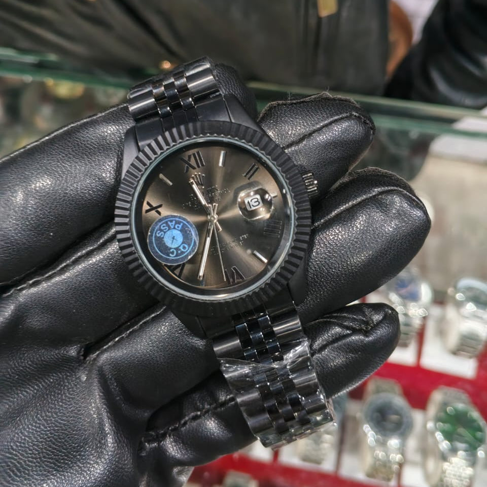 Black watch held in a gloved hand with a blurred background