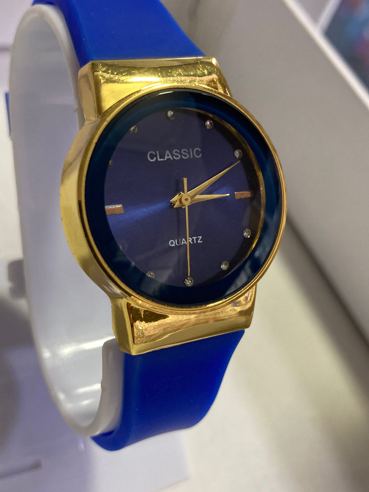 Gold-framed watch with blue face and strap on a white background