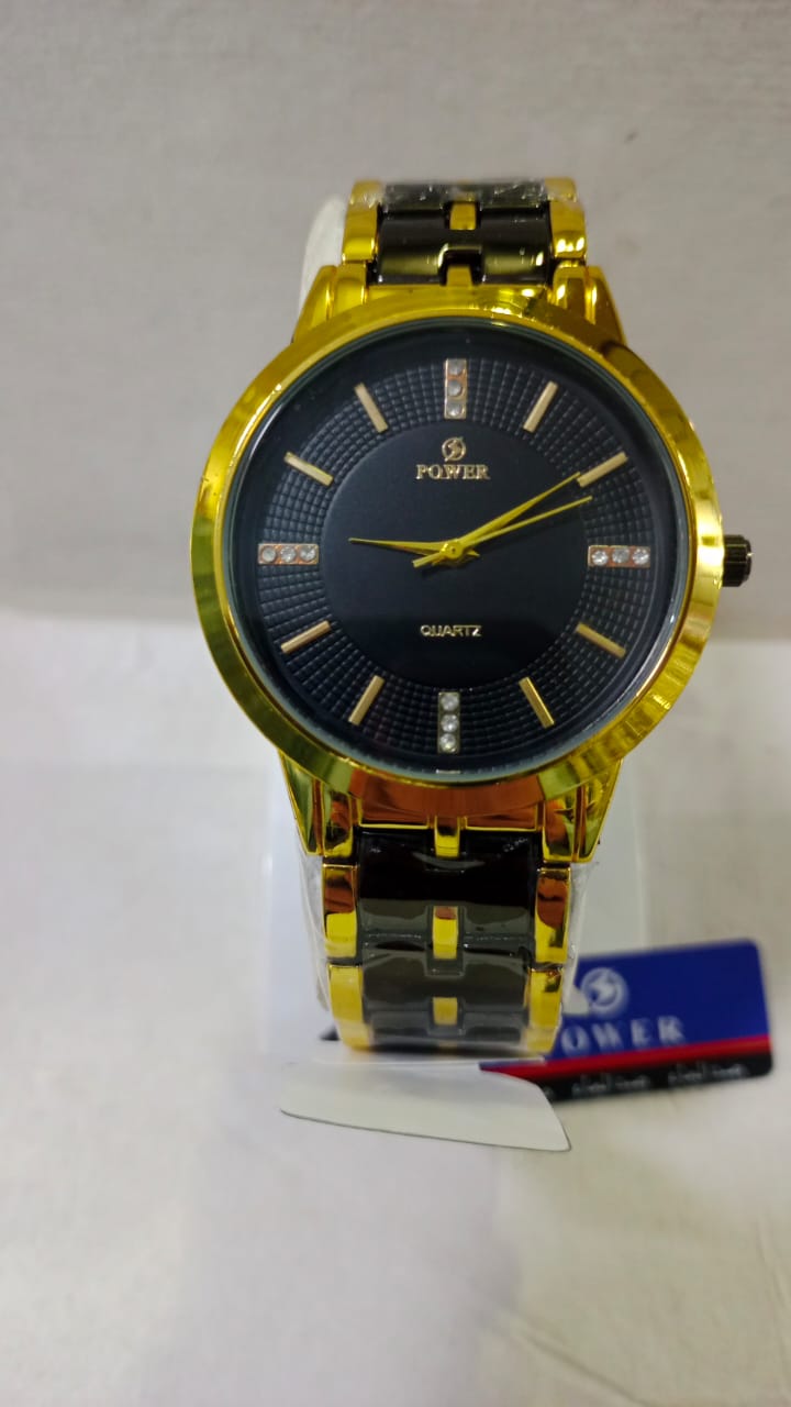 Gold wristwatch on a stand with Power brand packaging in the background