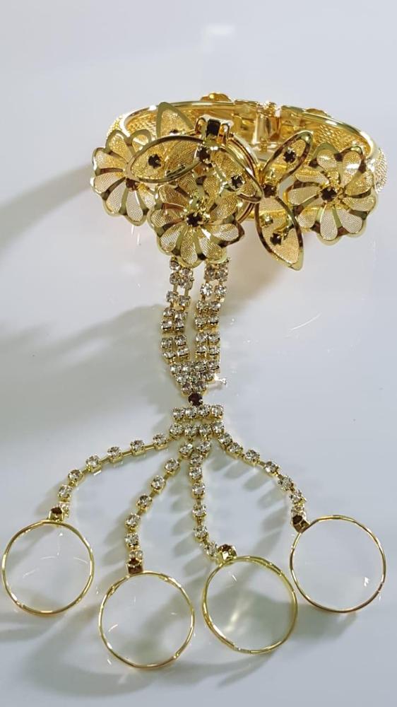 Gold bracelet with floral design and hanging elements on a white background