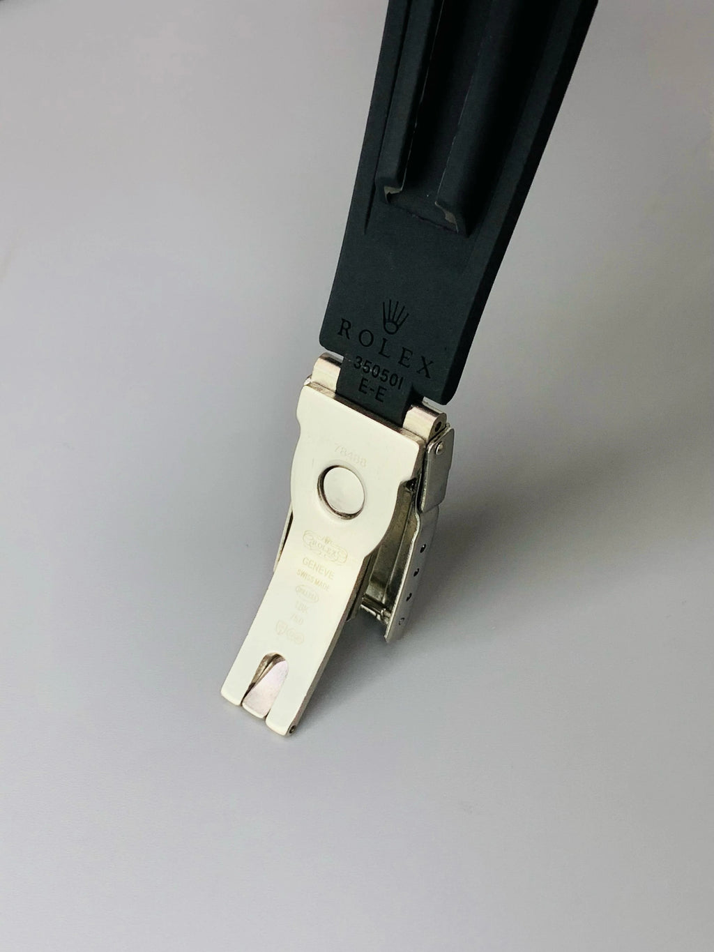 Close-up of a Rolex watch strap with a silver clasp on a gray background