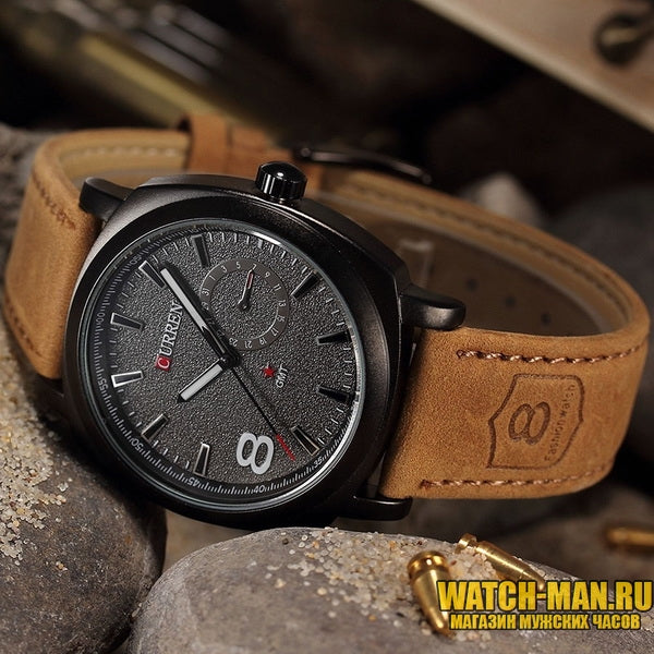 Wristwatch with brown leather strap and black dial on a stone surface, brand 'Curren' visible