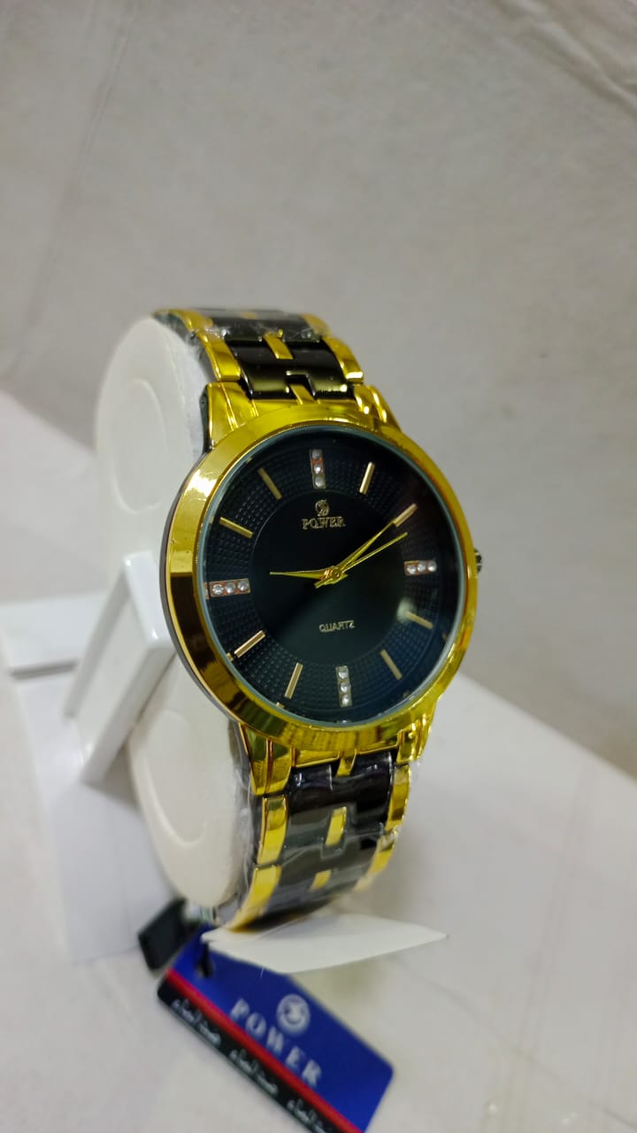 Gold and black watch on a white surface with a visible brand label.
