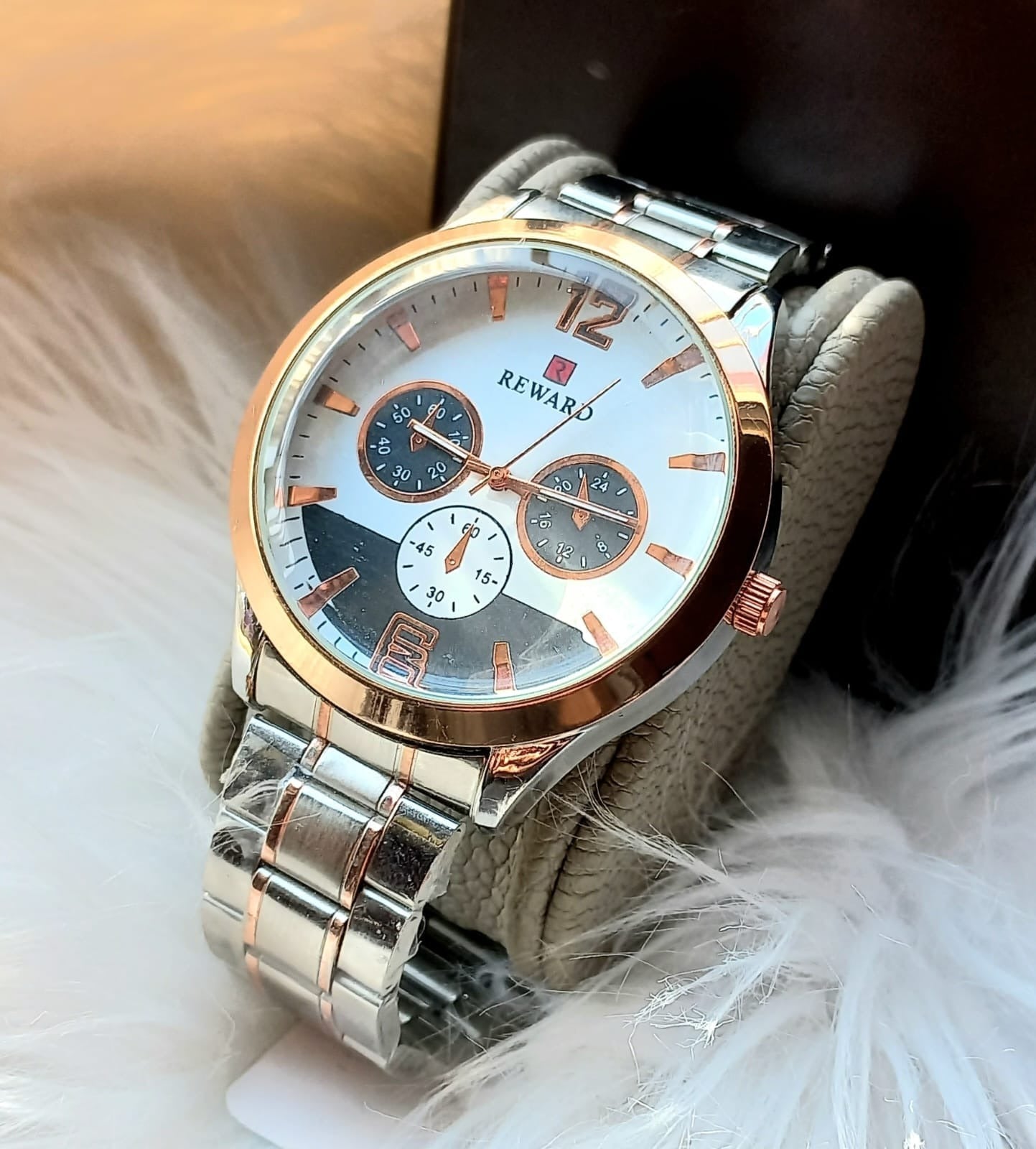 Silver and rose gold watch with 'Reward' brand on a white surface